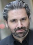 Michael Luongo image in black suit and shirt with beard and salt and pepper hair